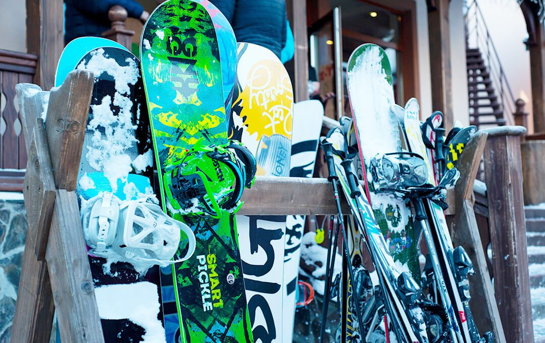 A close-up of snowboards placed on a rack in front of a ski and board rental store.