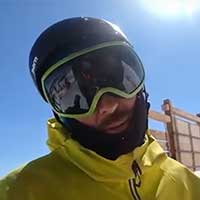 A close-up of Sean Flanagan's skiers and riders of AMR rentals and ski and board wearing a black helmet, goggles, and a yellow outer jacket.