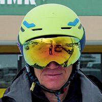 A close-up of Dave Stillman, owner and manager of AMR Rentals Ski and Board, wearing a yellow-green helmet and protective goggles.