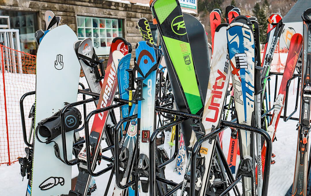A close-up of snowboards stacked on a snowboard rack in front of a ski rental shop.
