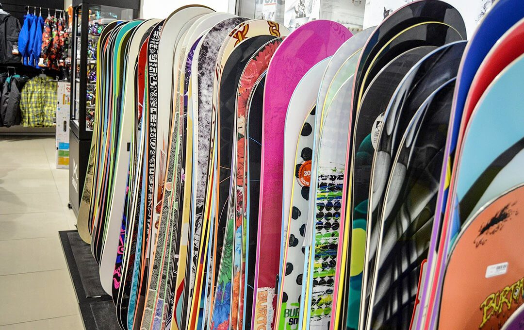 A close-up of snowboards displayed inside a ski and board rental shop.