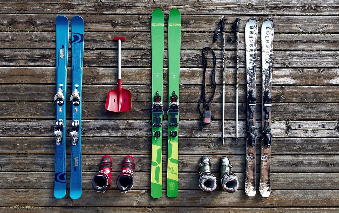 Overhead shot of skiing equipment placed on a wooden floor.