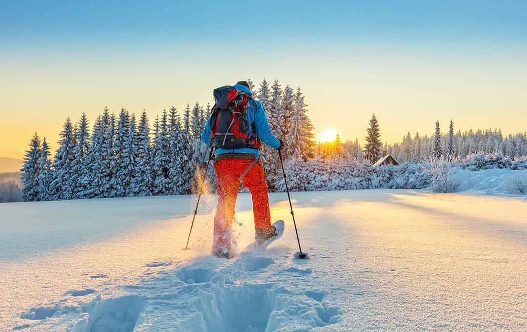 A hiker wearing skiing gear doing a snowshoeing activity